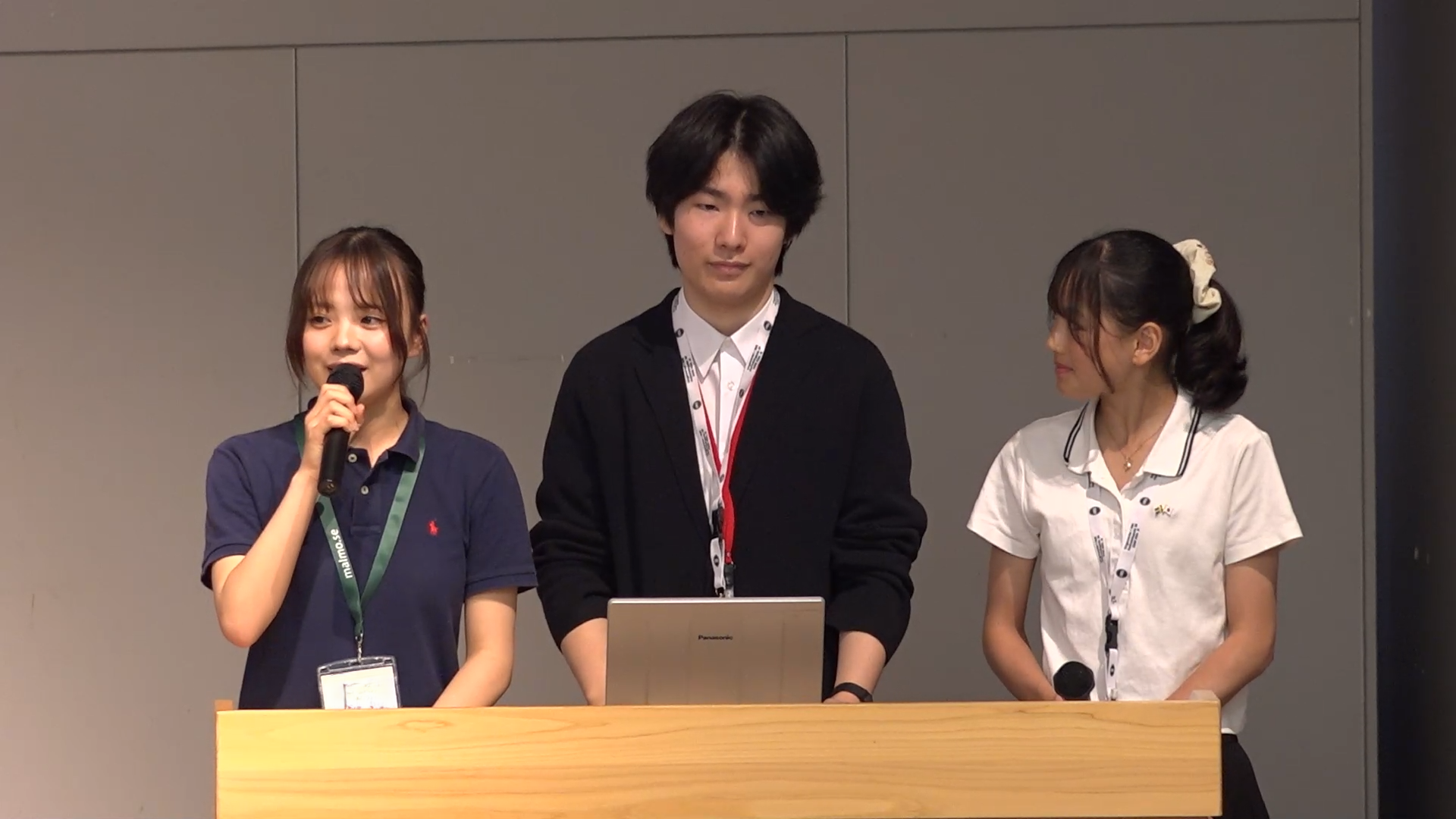 1人がマイクを持ち3名が壇上で発表している様子