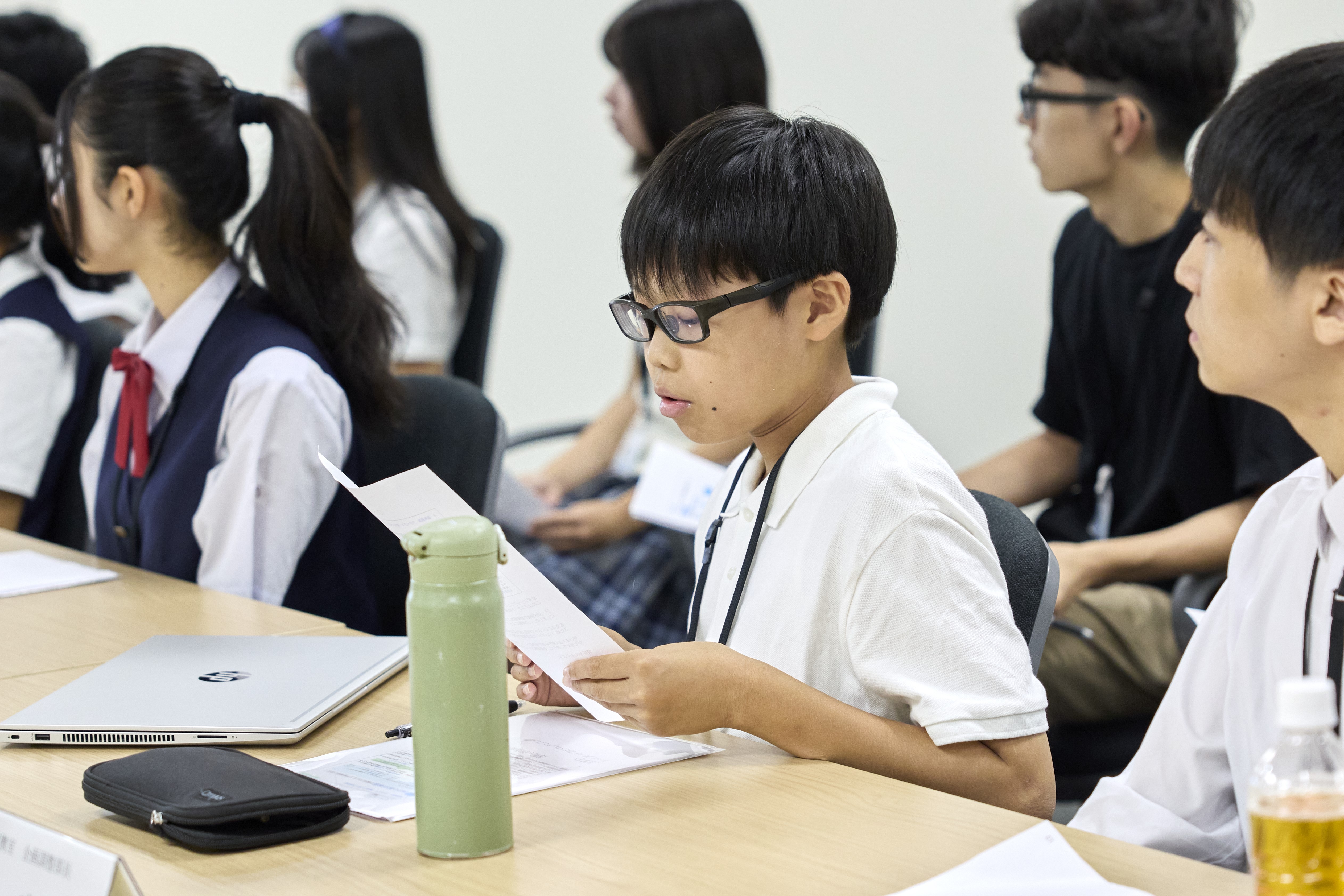 メガネをかけた中学生がレポートを読んでいる様子