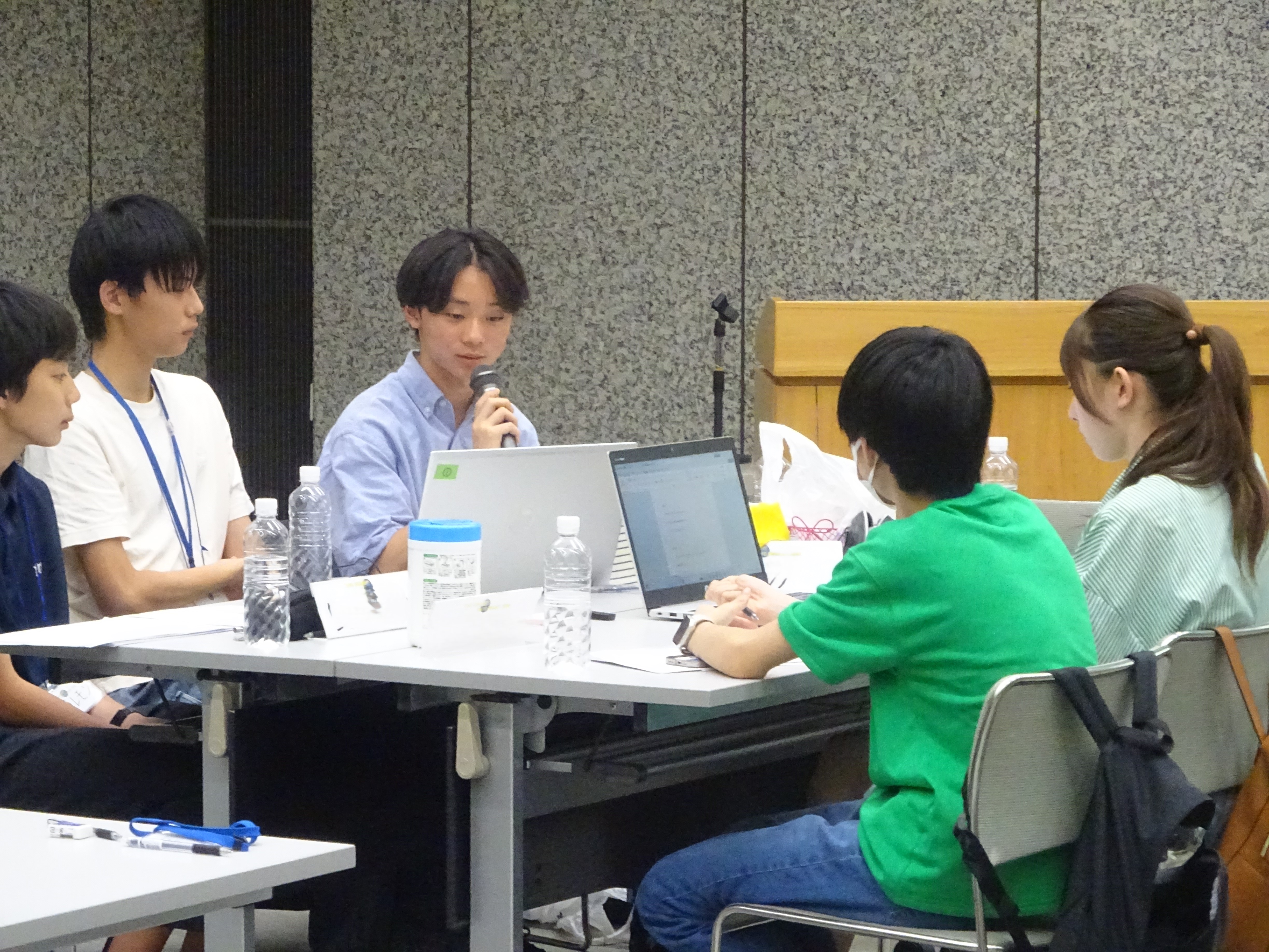 5名の中高生が机の席について話している様子